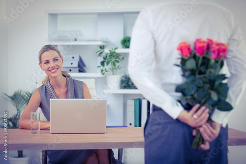  Man hiding bouquet in front of businesswoman at desk photo