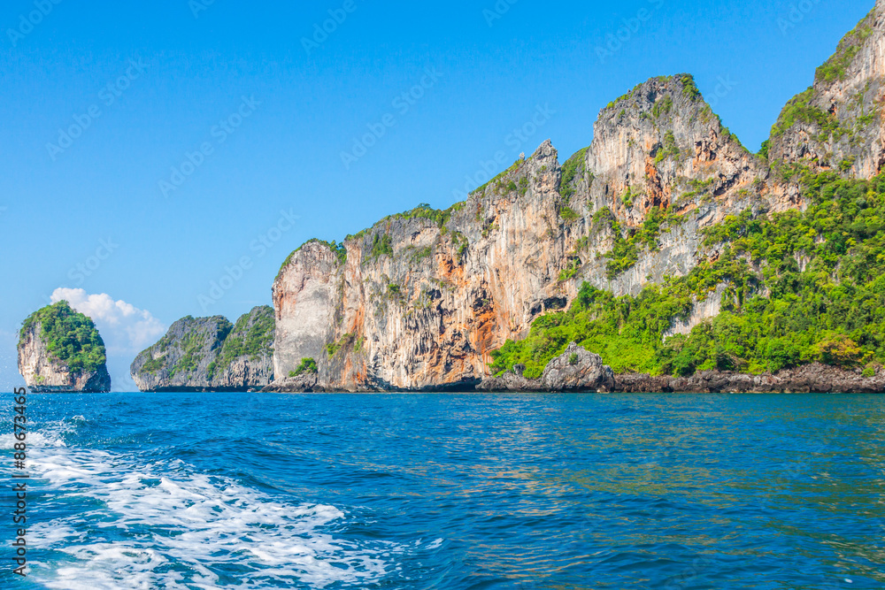 Cliff and the clear sea with a boat near Phi Phi island in south