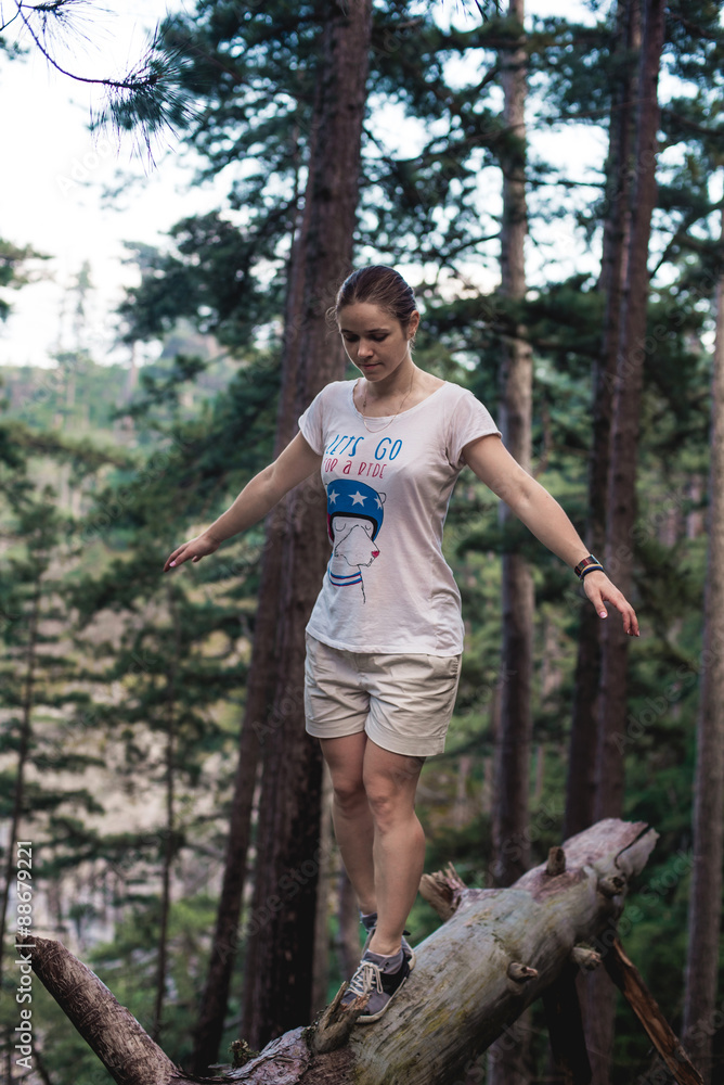 Caucasian hiker woman on trek in mountains living a healthy active lifestyle. Hiker girl on nature landscape hike in Crimea balancing on a tree, happy free female in the wood.