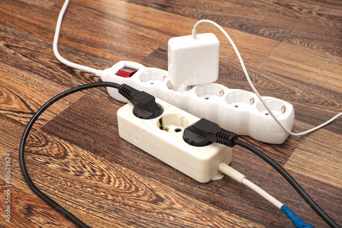 Many plugs plugged into electric power bars on floor