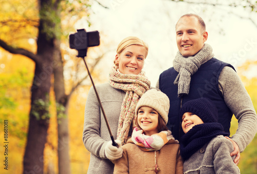 happy family with smartphone and monopod in park