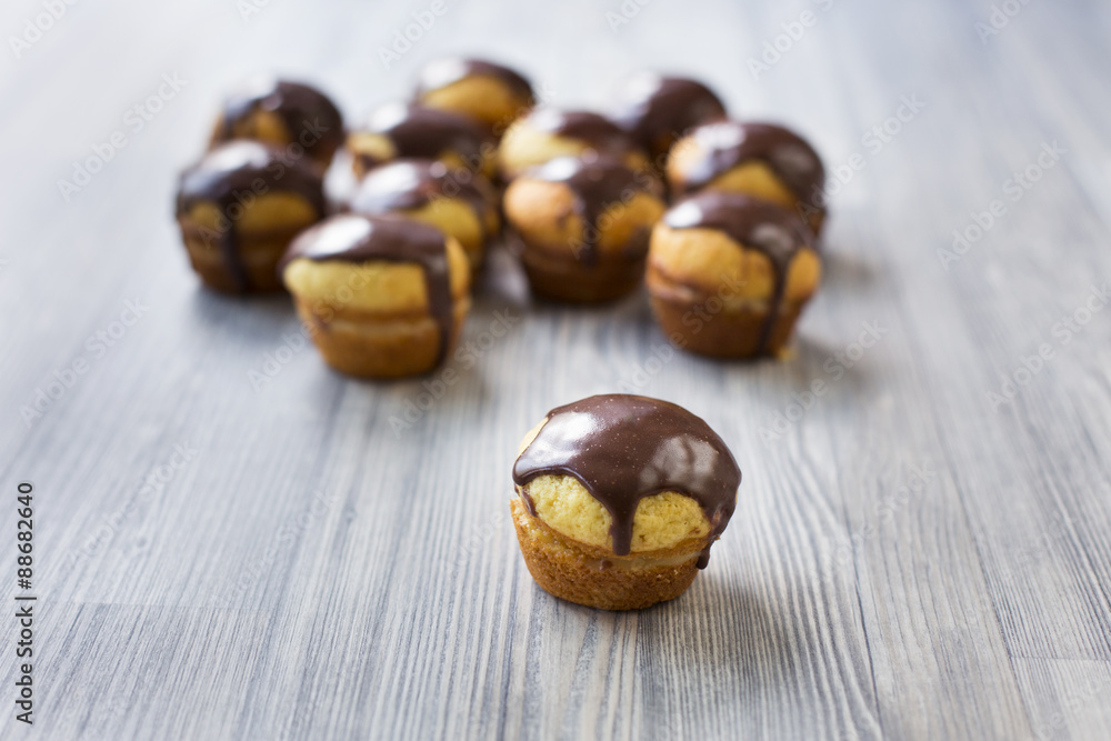 Obraz premium Cupcakes with vanilla cream and chocolate topping on grey wood stand
