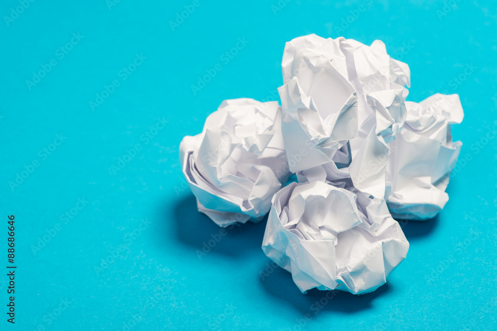 White color crumpled paper balls over the blue background