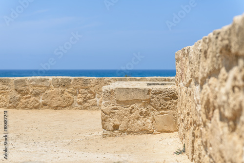 Ancient stone walls overlooking the blue Mediterranean Sea at an archaeological site in Paphos, Cyprus.