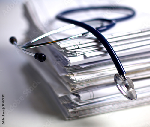 Medical stethoscope rests on a stack of documents