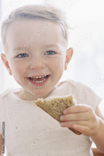 Portrait of a smiling young boy eating a sandwich. photo
