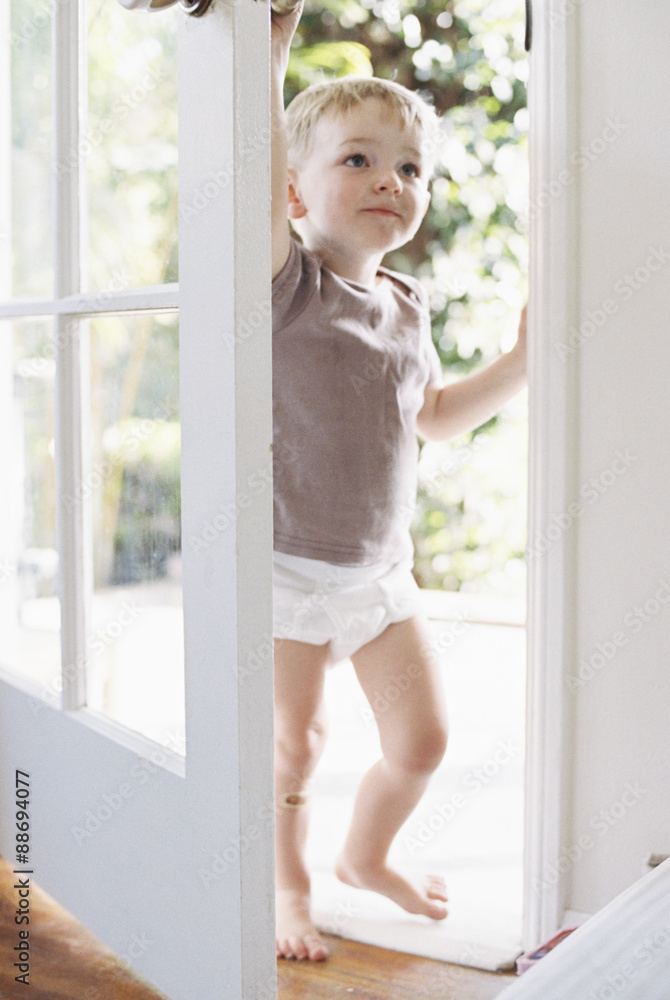 Young boy wearing T-Shirt and pants, opening a door. Young boy wearing T-Shirt and pants, opening a door.