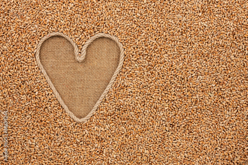 The symbolic heart made of rope lies on sackcloth and wheat grai photo