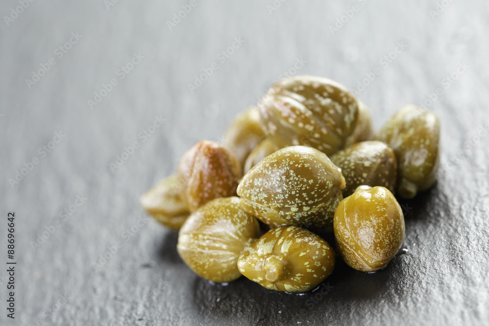 Obraz premium marinated capers in olive bowl on slate board