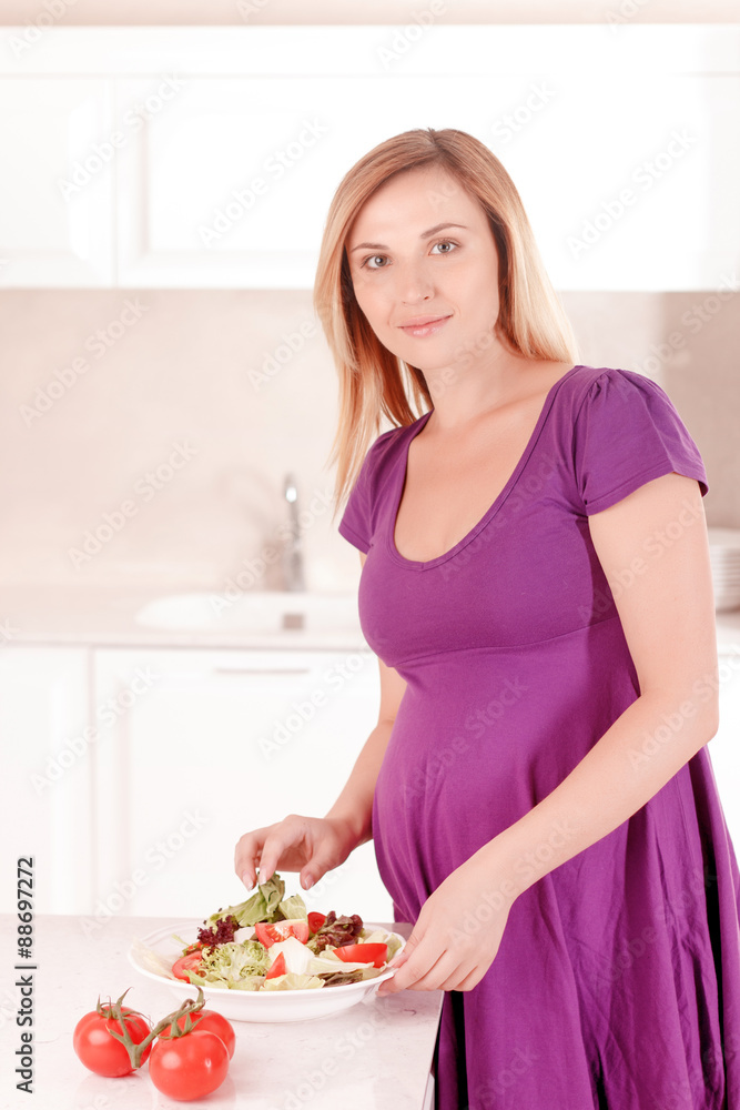 Pregnant woman making salad in kitchen Pregnant woman making salad in kitchen
