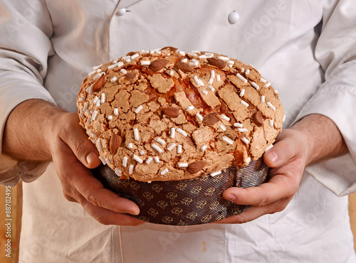 Manos de un panadero sujetando un panettone recien horneado. photo