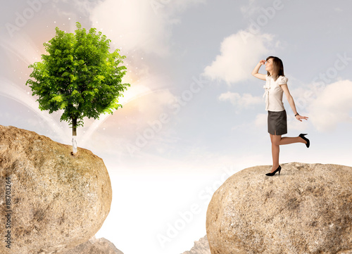Businesswoman on rock mountain with a tree