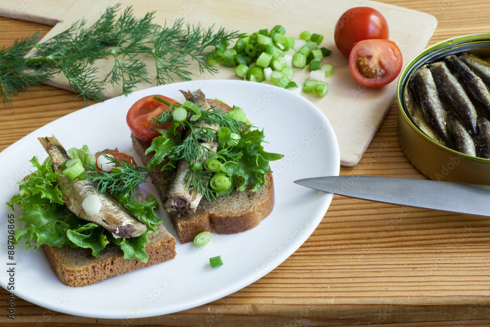 sprats, bread, onion and tomatoes on a table sprats, bread, onion and tomatoes on a table