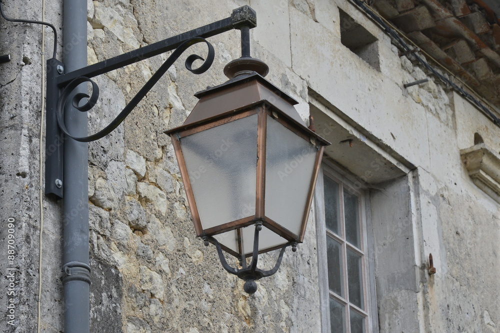 Lampe électrique sous forme de réverbère rustique  suspendue à l'une des façades du Périgord Noire