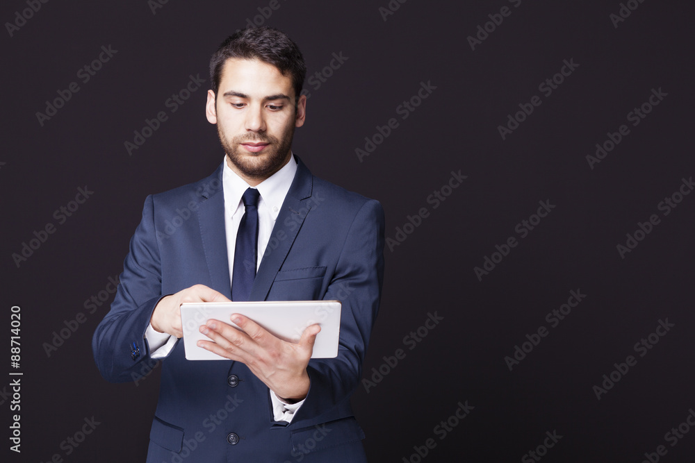 Businessman standing with a tablet computer on black background Businessman standing with a tablet computer on black background