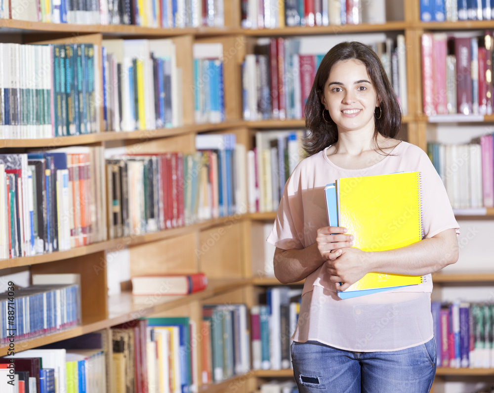 Cute female student holding notebooks at the university library Cute female student holding notebooks at the university library