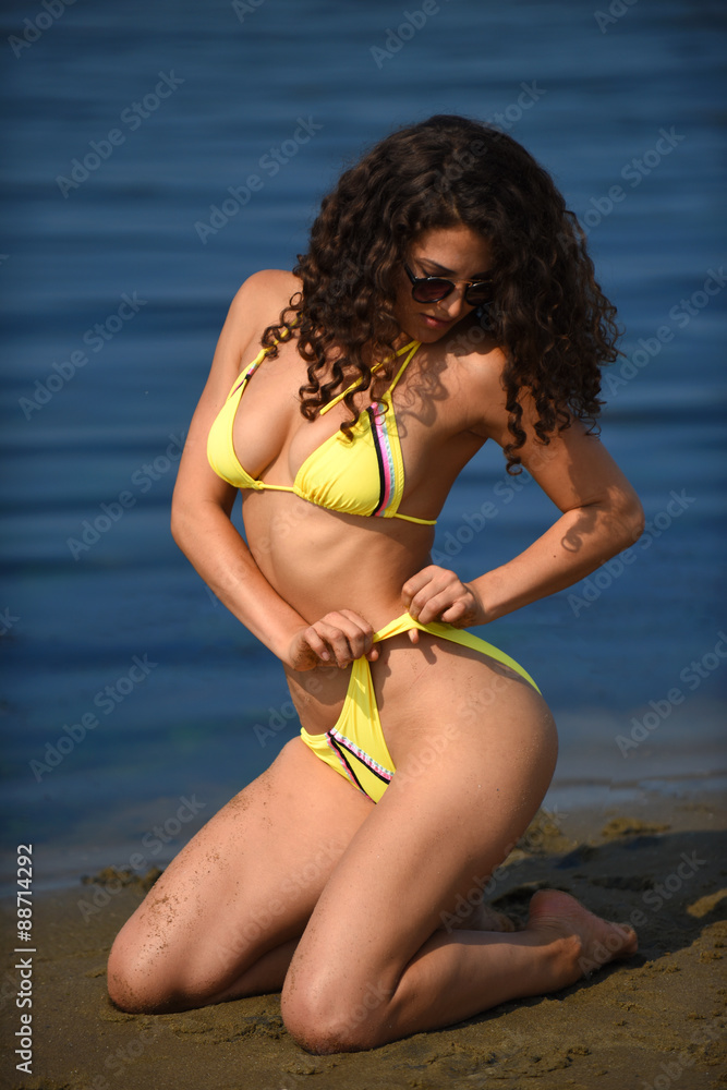 Attractive young woman with slim and fit body wearing yellow bikini posing  sexy on the tropical beach. Stock Photo | Adobe Stock