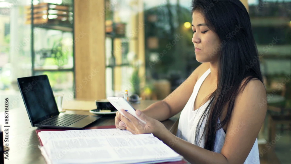 Young female student doing homework with smartphone in cafe
Young female student doing homework with smartphone in cafe