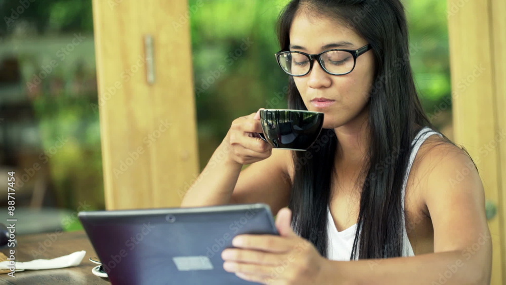 Young female student reading something on tablet computer and drinking coffee in cafe
Young female student reading something on tablet computer and drinking coffee in cafe