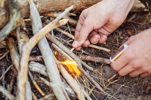 man kindles a fire in summer wood photo