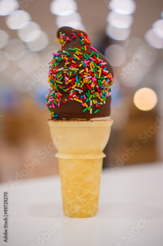 Ice cream waffer cone with chocolate and sprinkles on blurry bac