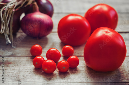 Tomatoes and onions on wooden background