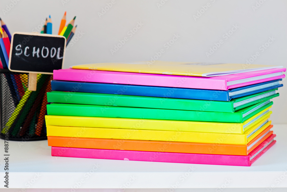Fototapeta premium Multi colored books in stack on the light-coloured bookshelf
