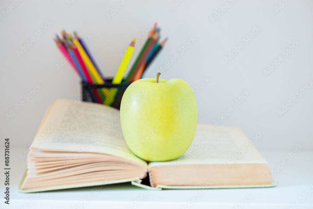 A yellow apple sitting on opened book