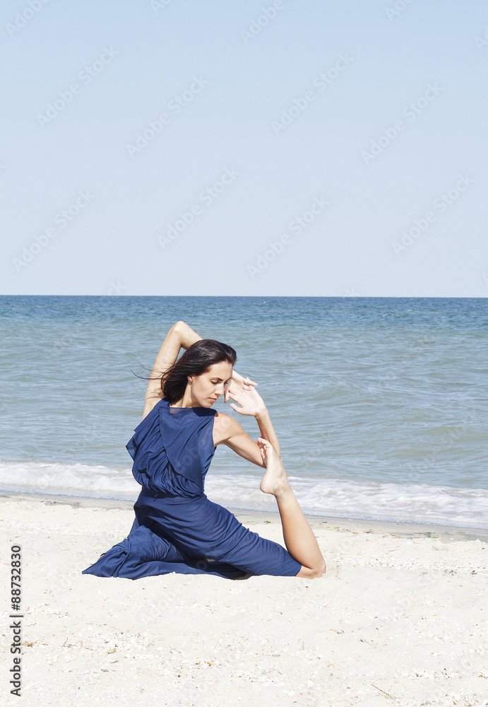Young beautiful woman doing yoga at seaside in blue dress Young beautiful woman doing yoga at seaside in blue dress