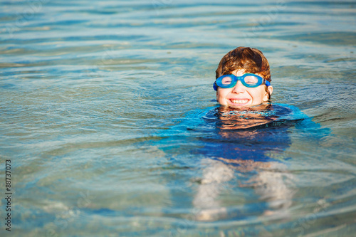 Happy smiling boy with goggles on swim in shallow water © x4wiz