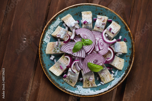 Plate with sliced herring filet, dark wooden surface, above view