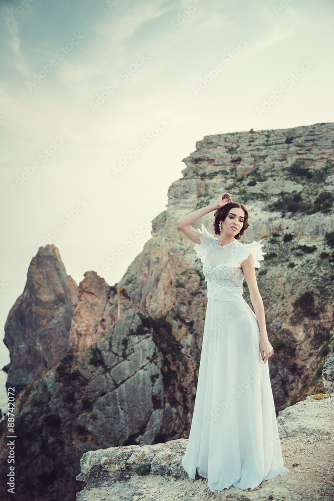 Beautiful bride posing on the coast with angelic dress.