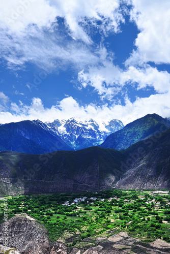 green rolling mountains and snow mountains of rural countryside with green fields and villages