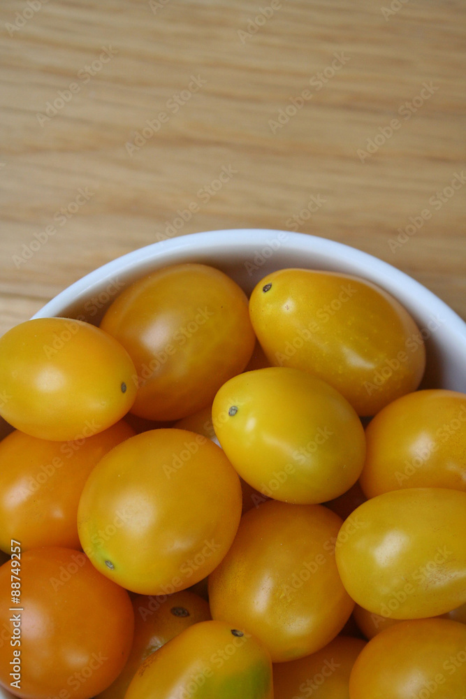pomodorini gialli su ciotola su tavolo di legno