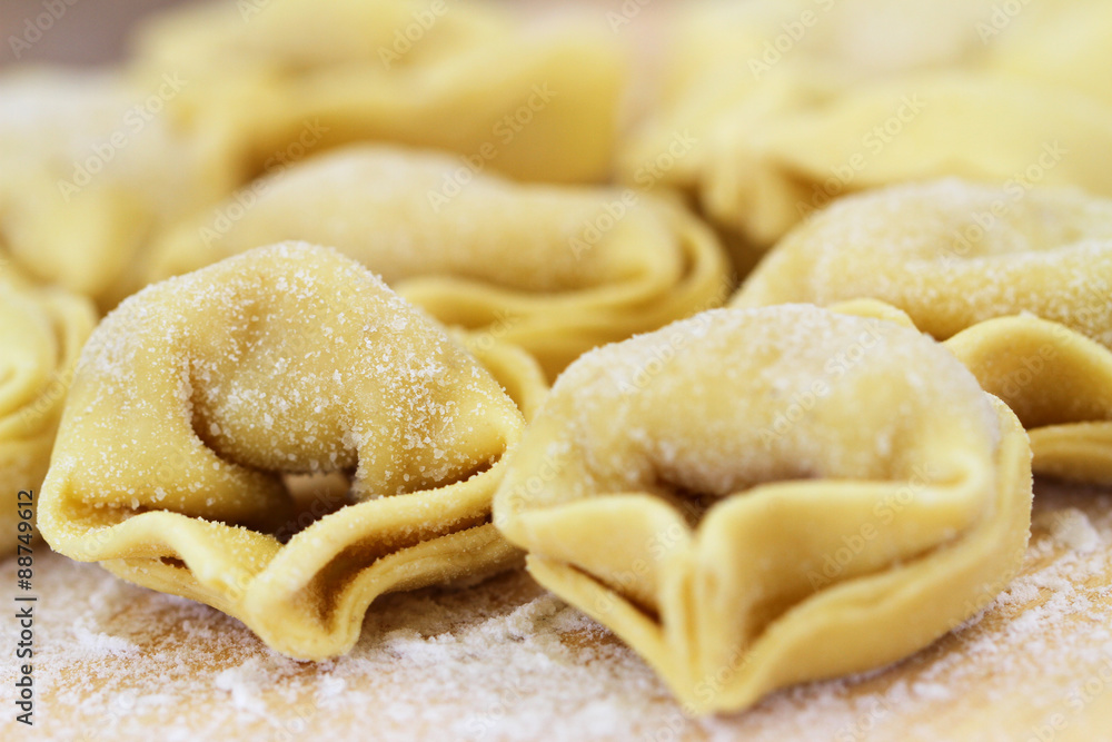 Uncooked tortellinis sprinkled with flour, closeup
