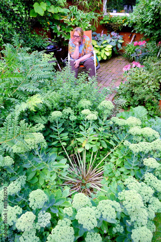 Woman sitting in garden surrounded by plants