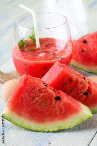 Couple of melon slices in front of fruit smoothie