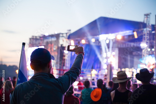 young man taking pictures rock concert on phone