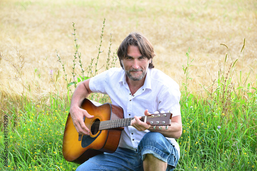 A man with a guitar in a field