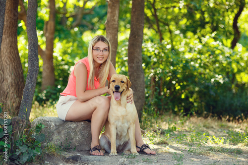 portrait of Beautiful young girl with her dog labrador retriever outdoor in summer beautiful park