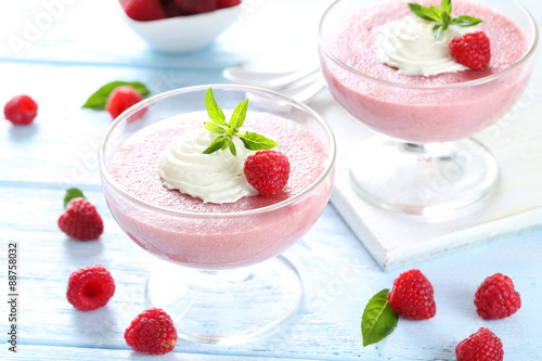 Sweet raspberry mousse in glass on blue wooden table