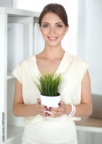 Beautiful woman holding pot with a plant
