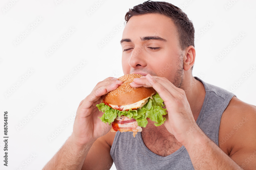Attractive young man is eating unhealthy hamburger Attractive young man is eating unhealthy hamburger