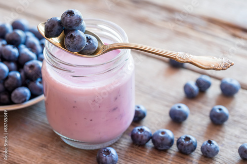 Fresh blueberries yogurt in glass jar, spoon and saucer of bilbe photo