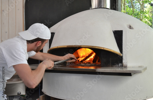 Panadero cocinando pizza en un horno a leña