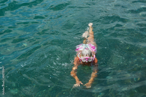 Aged woman is swimming with goggles in the sea.