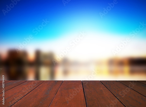 Brown wooden floor with blurred sunset background.