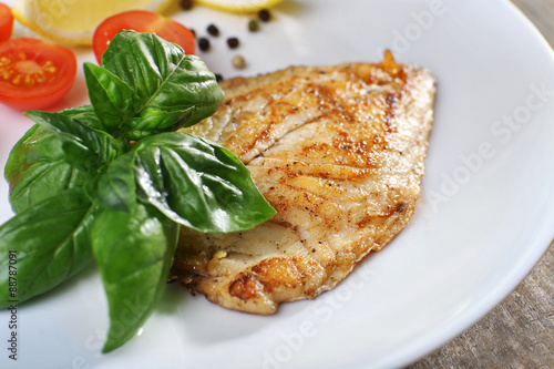 Fototapeta Naklejka Na Ścianę i Meble -  Dish of fish fillet with basil and lemon on plate close up