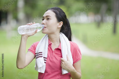 sporty woman drinking water from a bottle after jogging or runni