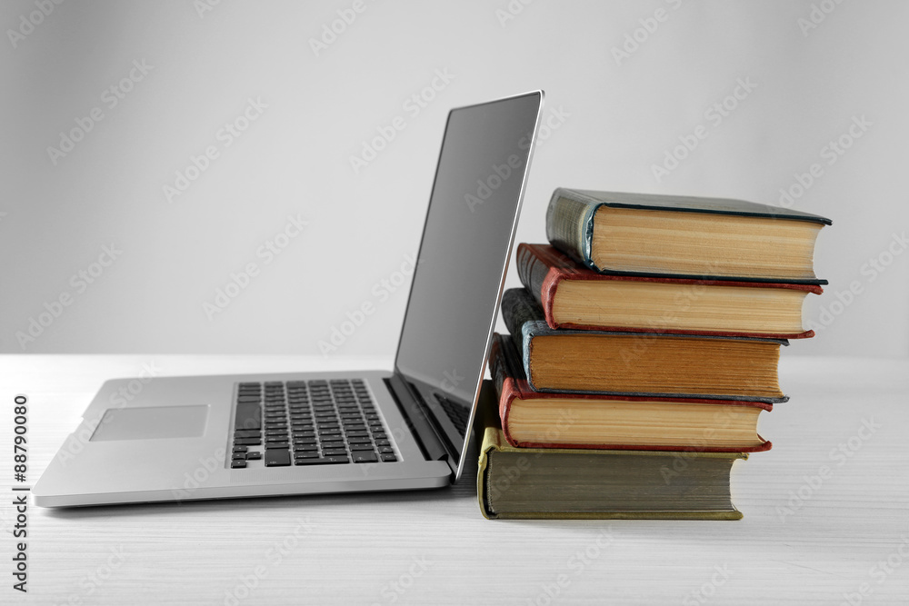 Stack of books with laptop on gray background Stack of books with laptop on gray background